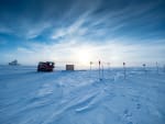 Sun low in sky, over IceCube Lab in distance on horizon.