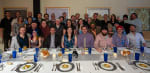 Group photo, seated at long table for midwinter meal.