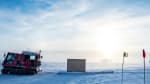 Sun low in sky, over IceCube Lab in distance on horizon.