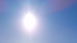 Person walking in distance under bright sun with sun halo.