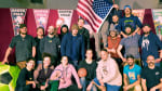 Group photo of South Pole Polympics participants, one holding up US flag.