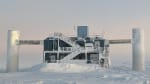 The IceCube Lab at sunrise, with South Pole Telescope visible in distance.