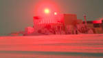 A bright streak of aurora in the sky seeming to shoot forth from a winterover’s forward-stretched arm.