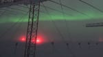 Winter skies and auroras seen through row of large antenna structures in the foreground.