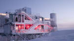 Angled view of frosty IceCube Lab during early sunrise.