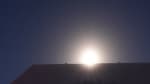 Bright moon centered over and peaking above the South Pole Telescope.