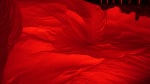Large snowdrift brightly illuminated in red, all else dark in background.