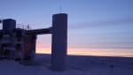 The IceCube Lab in shadow at twilight, with orange light just beginning to appear on horizon.