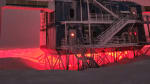 IceCube Lab in winter, backlit in red lights, starry sky overhead.