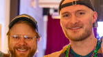 Close-up on three people smiling for the camera, wearing colorful shirts.