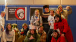 Group photo, some in space-related costumes, in front of poster for Yuri’s Night.