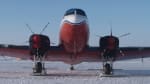 Front view of a Basler plane parked on the ice at the South Pole under blue skies.