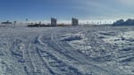 Distant view of drill camp, centered on two separated drill towers, under sunny sky.