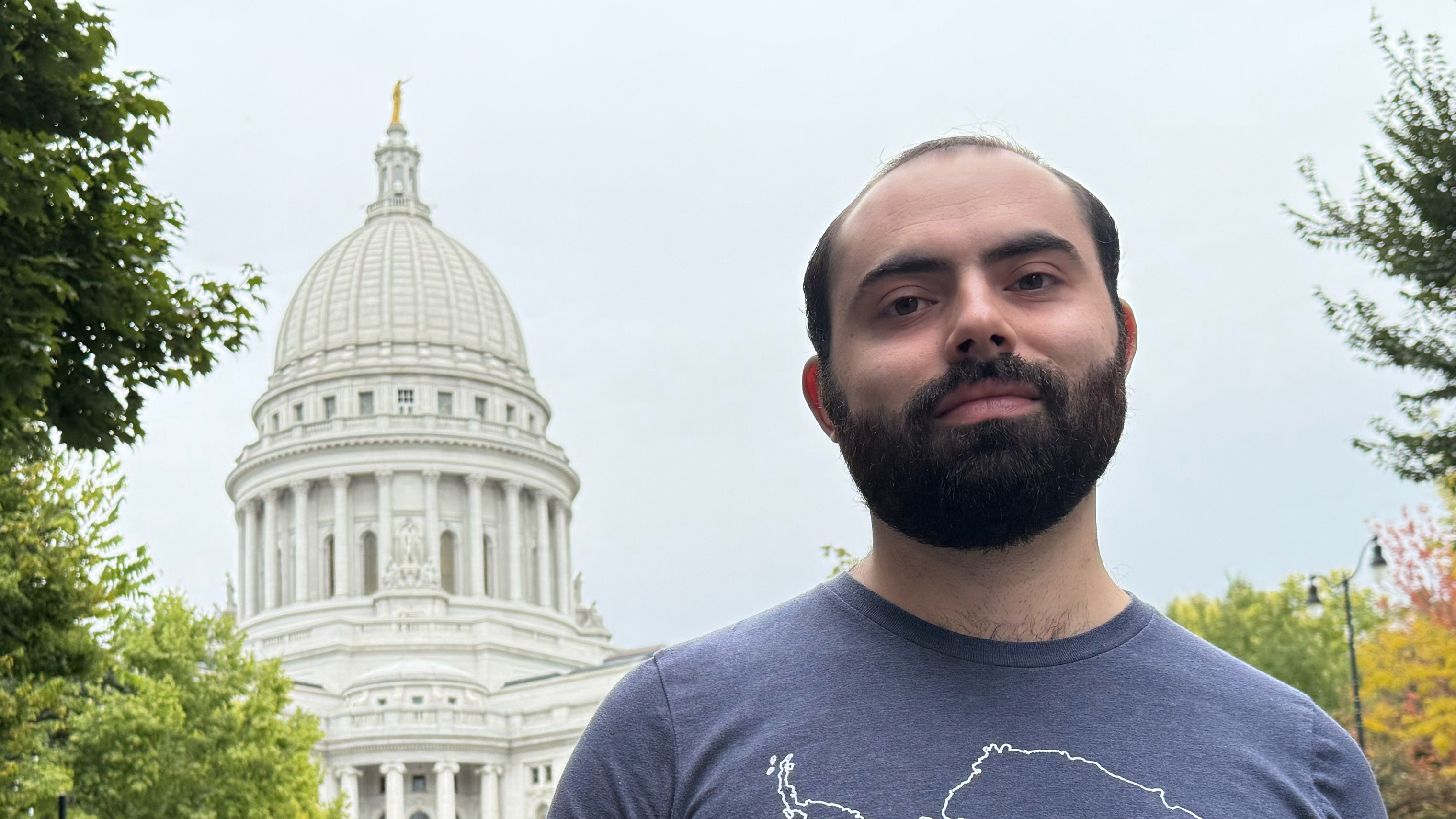 A man posing for a photo in front of the Madison, WI capitol building