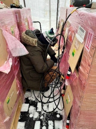 Worker crouching between crates while testing modules.