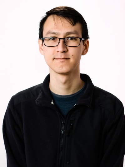 A headshot of a man in a black sweater and glasses.