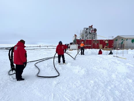 Line of people holding long cable between them.