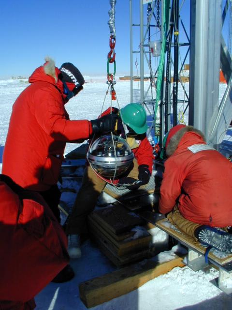 A photo of a DOM being deployed at the South Pole.