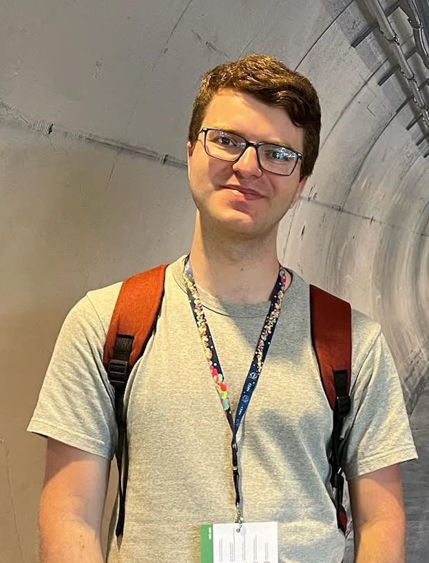 A headshot of a man with a bagpack and glasses.