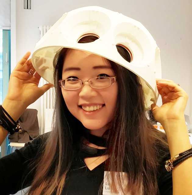 A woman with a white dome on her head, smiling