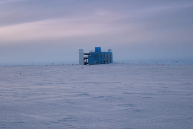 The IceCube Lab seen from a distance, with a darkening cloudy sky before sunset.