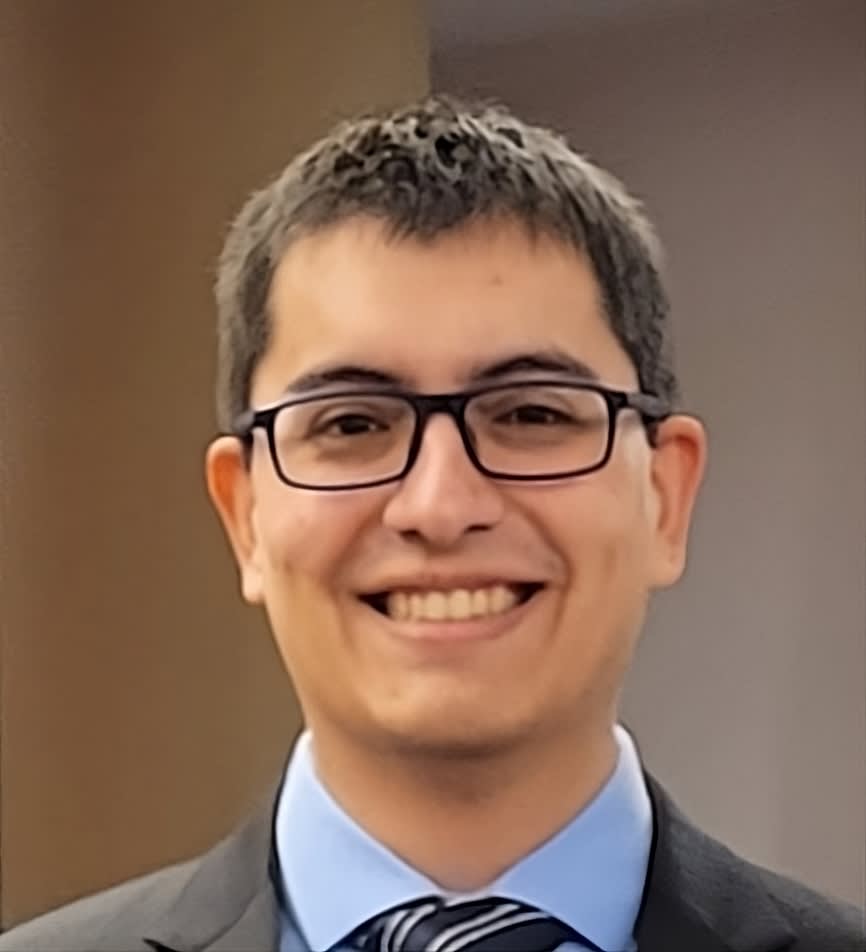 A headshot of a man with glasses and a suit and tie.
