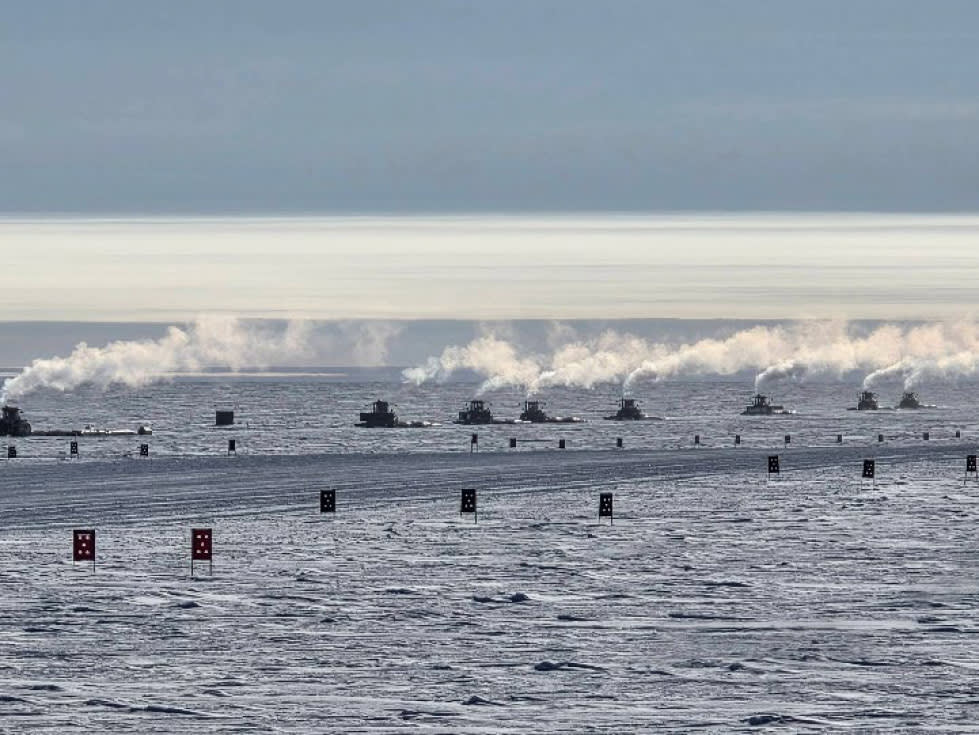 Steam emanating from tops of chain of traverse vehicles in the distance.