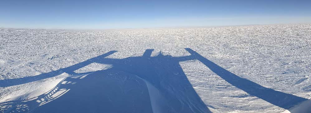 South Pole horizon with nothing visible except for long shadow of the IceCube Lab (in foreground).