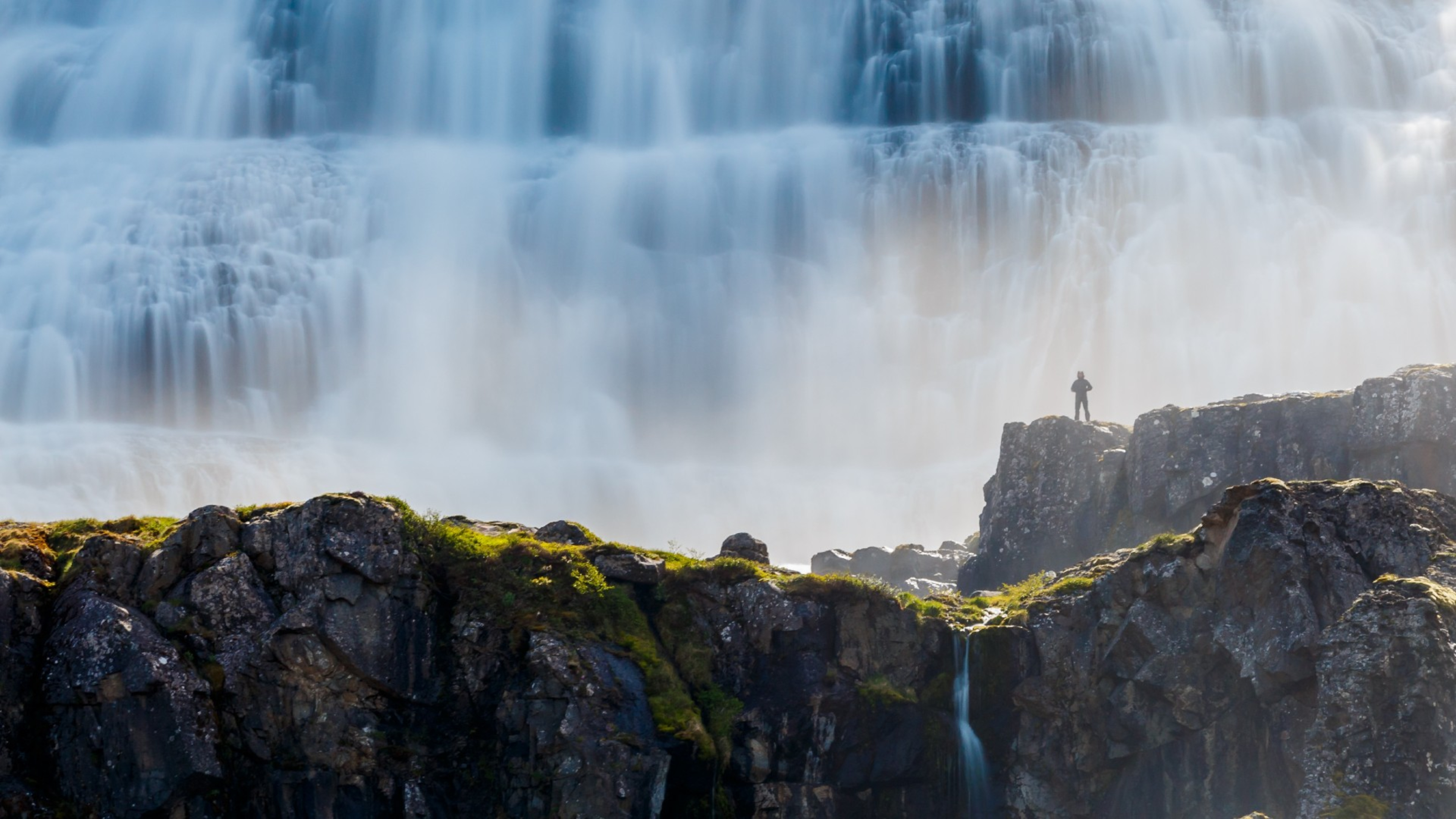 Person at the base of Dynjandi waterfall, Westfjords, Iceland.