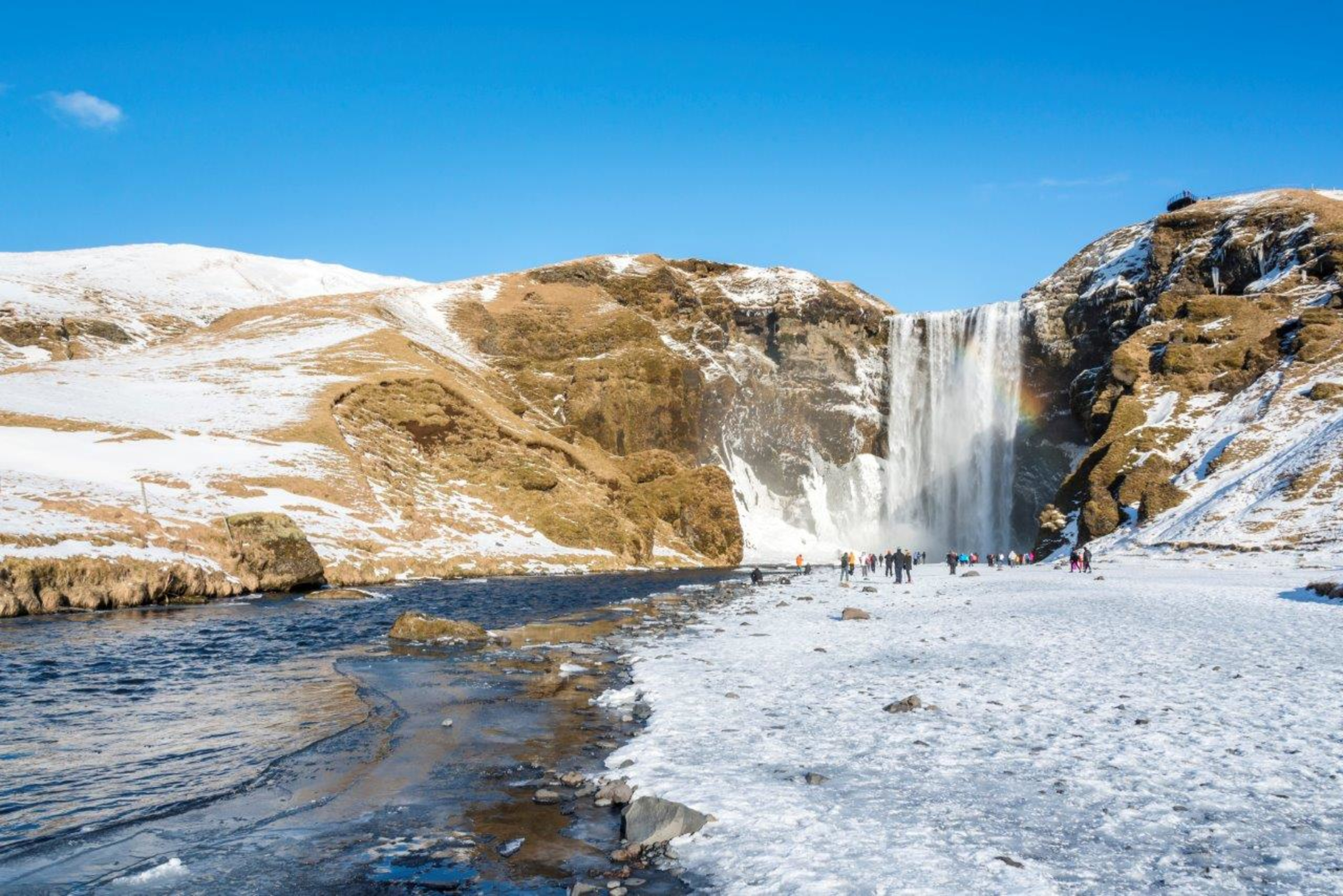 Skogafoss waterfall in the snow with blue skies above