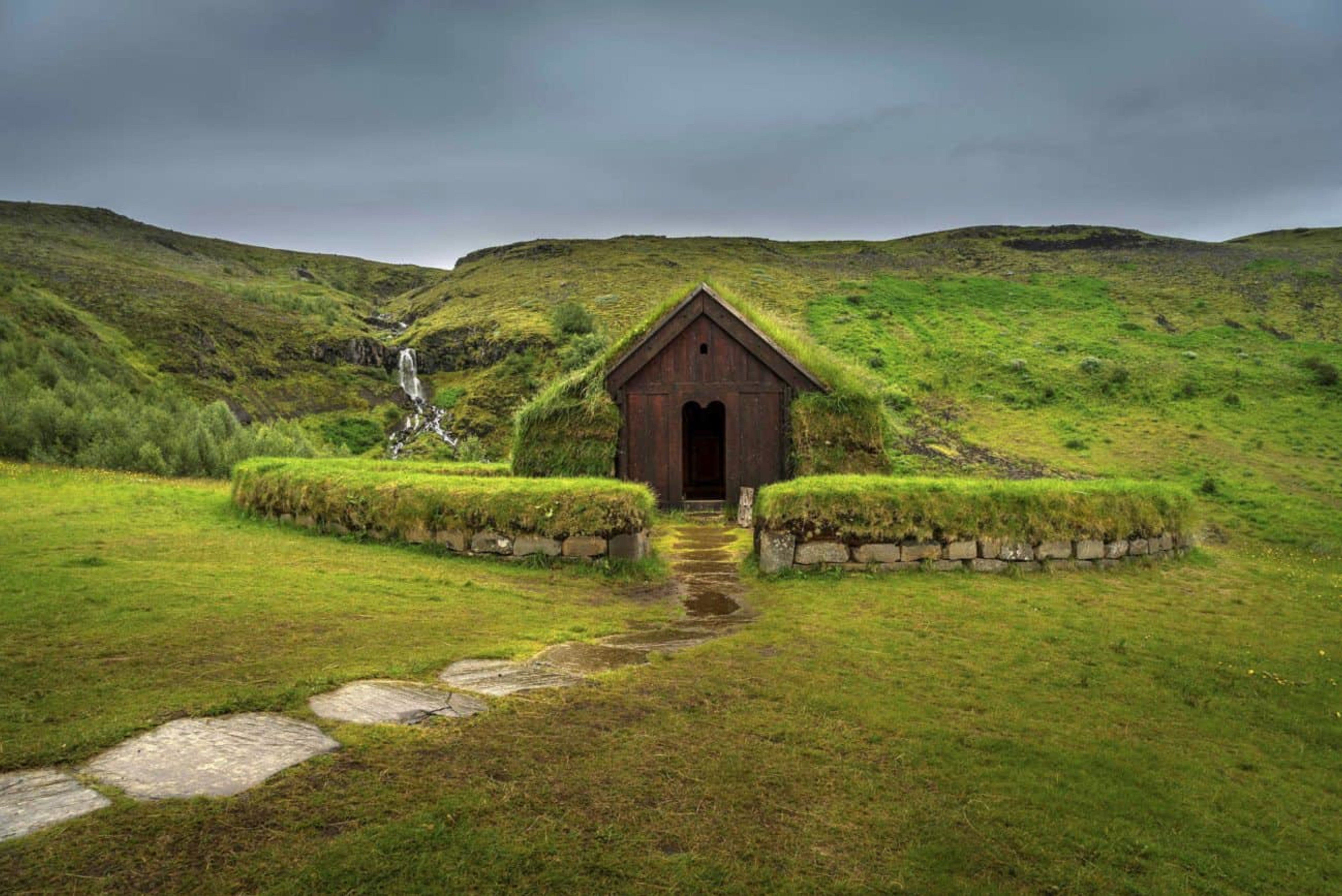 turf house with round enclosure and green hills in background