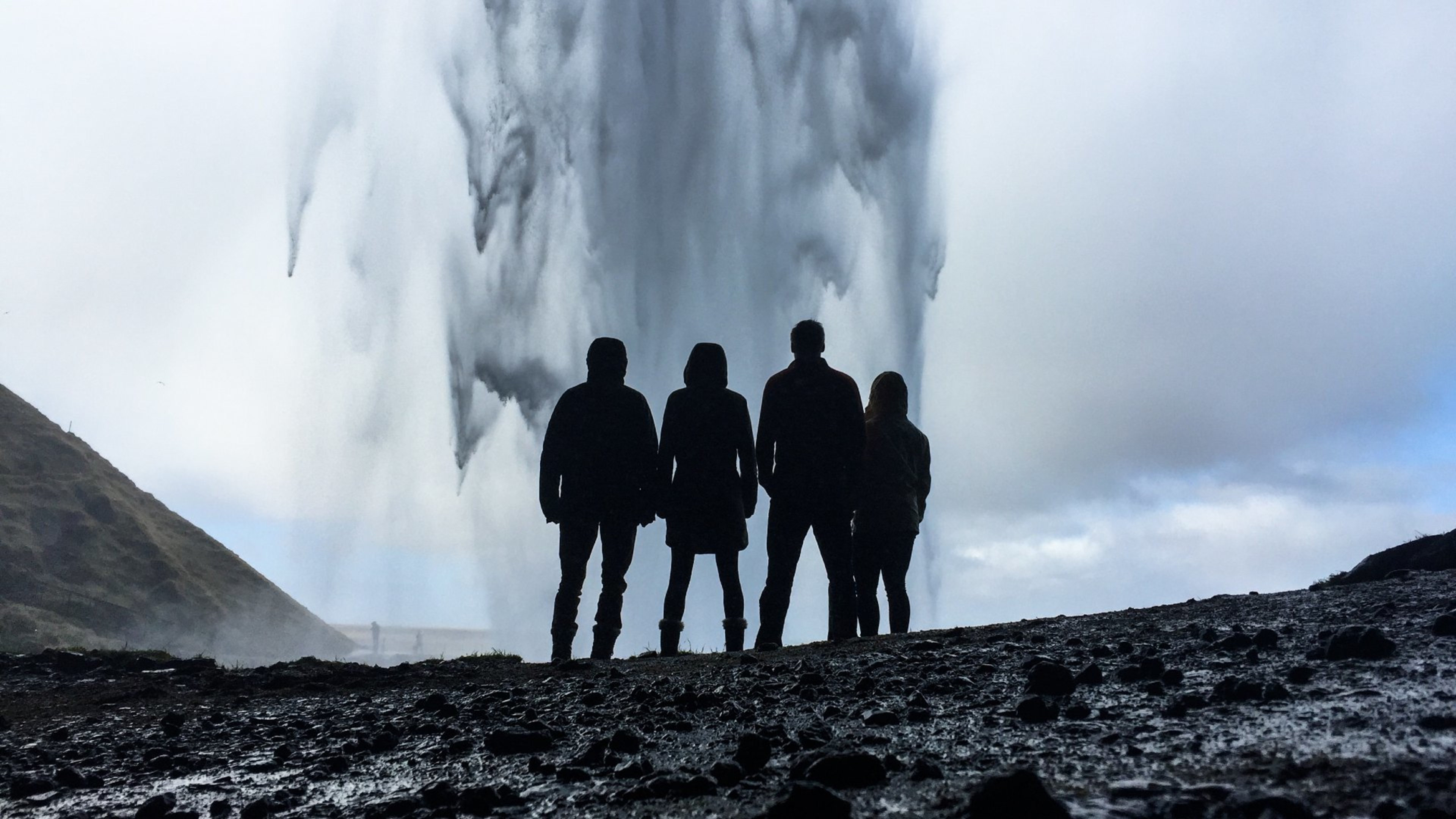 A group of people standing behind Seljalandsfoss