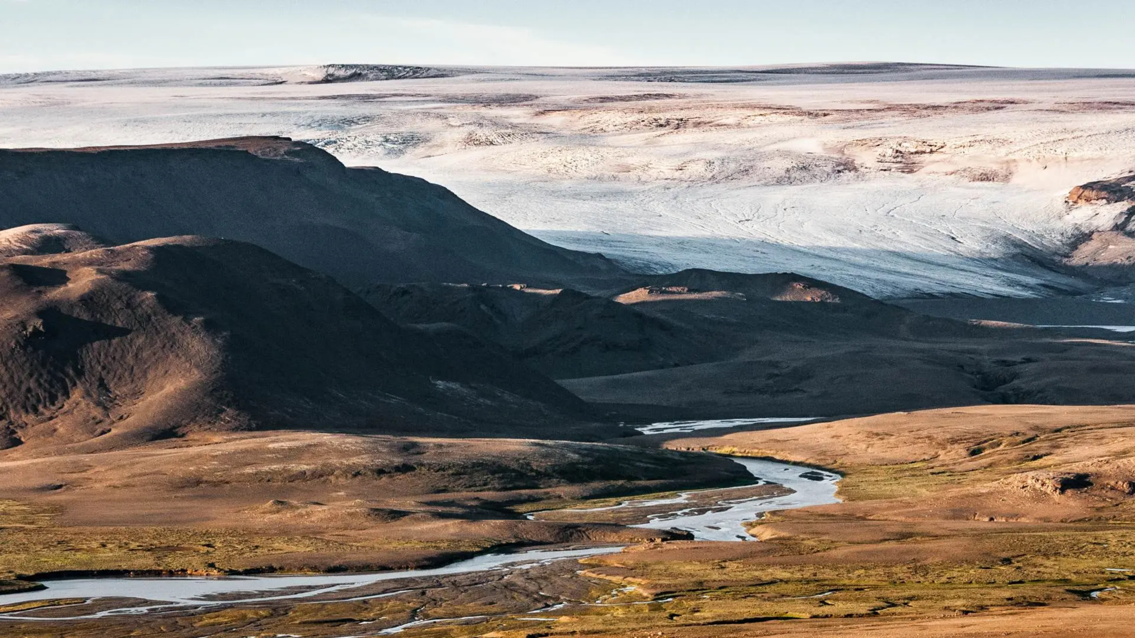 river running below glacier and mountains