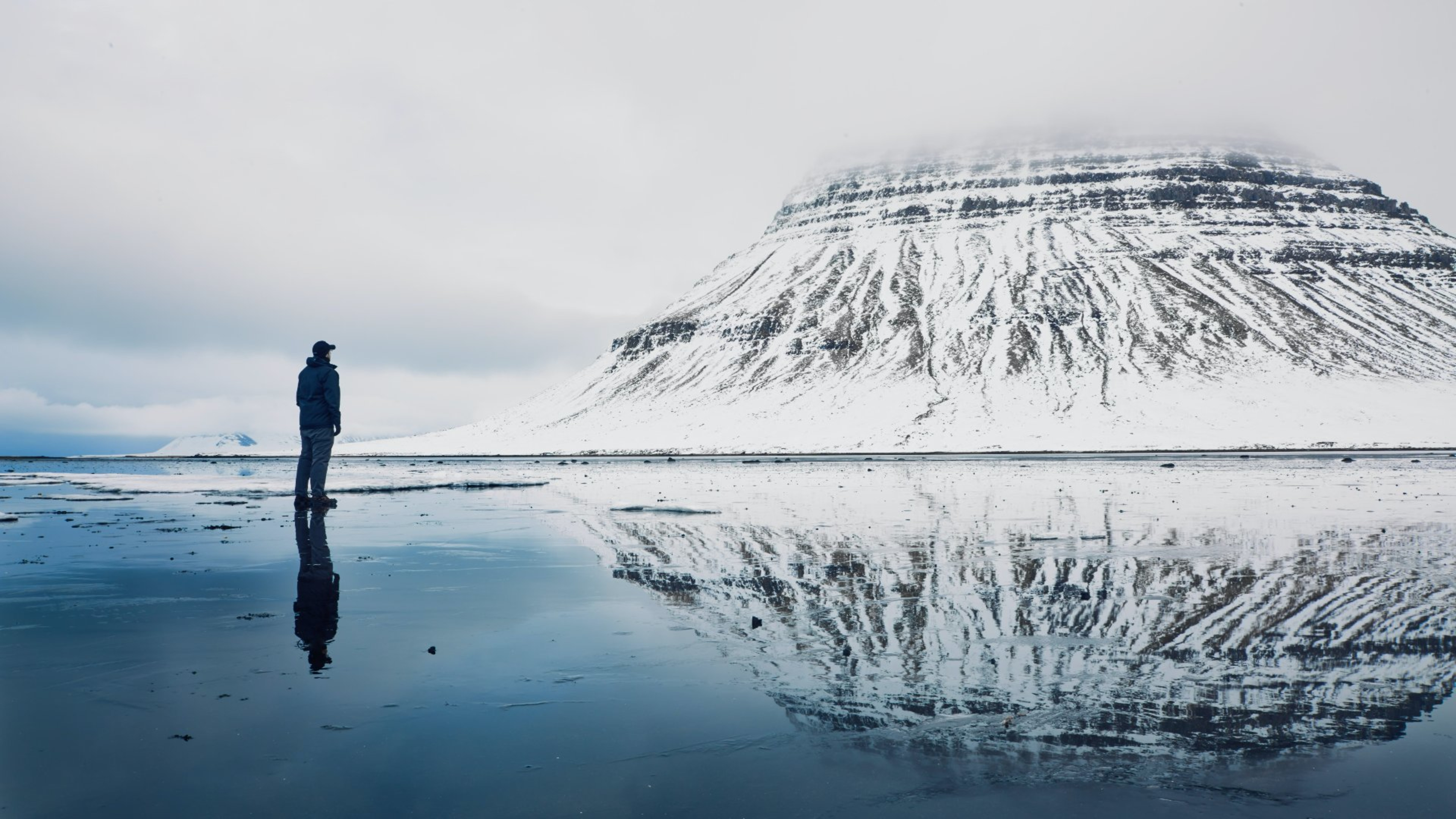 A man looking at the Kirkjufell mountain covered in snow