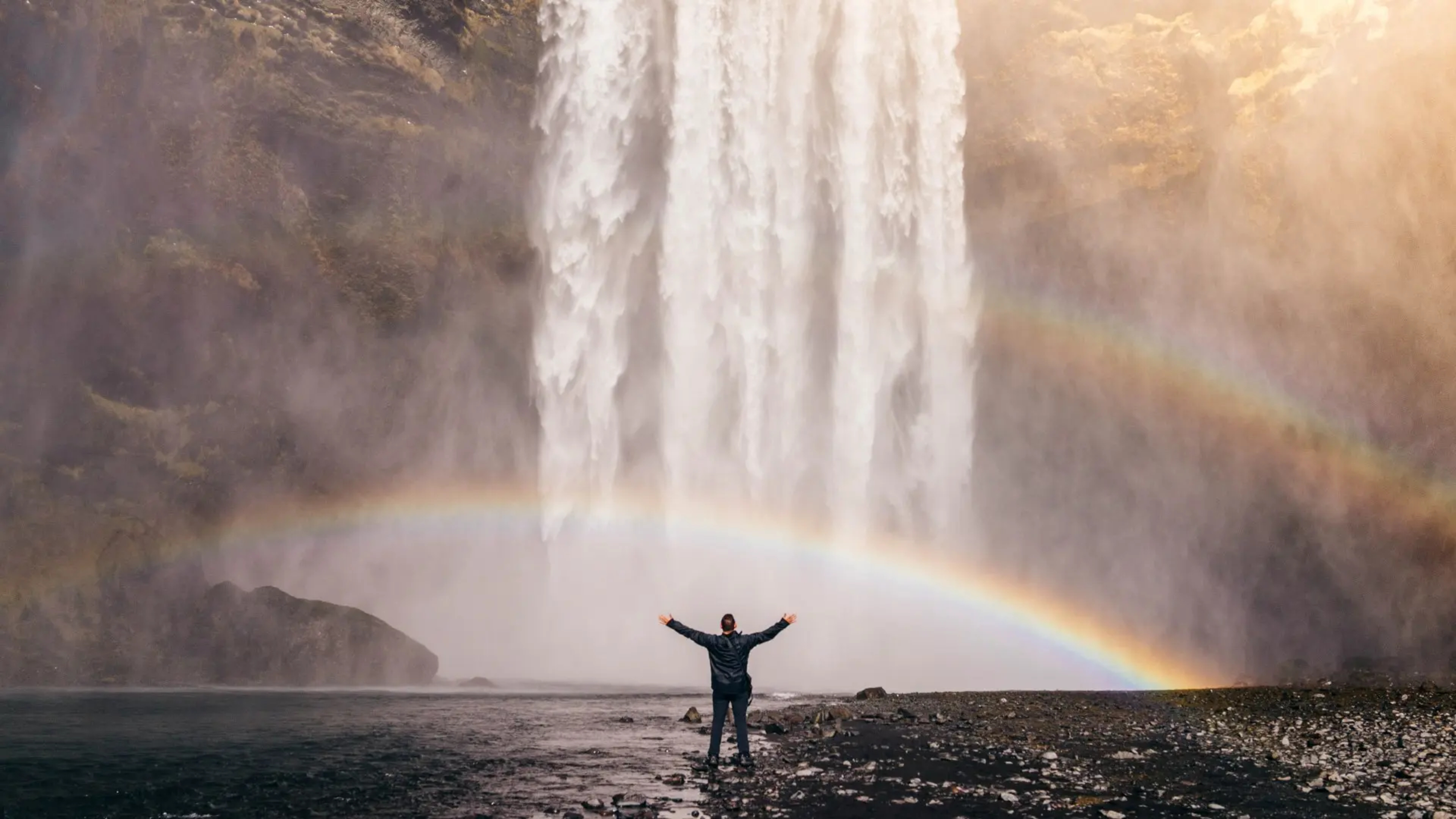 man-at-skogafoss-with-rainows-jared-erondu-unsplash.jpg.webp