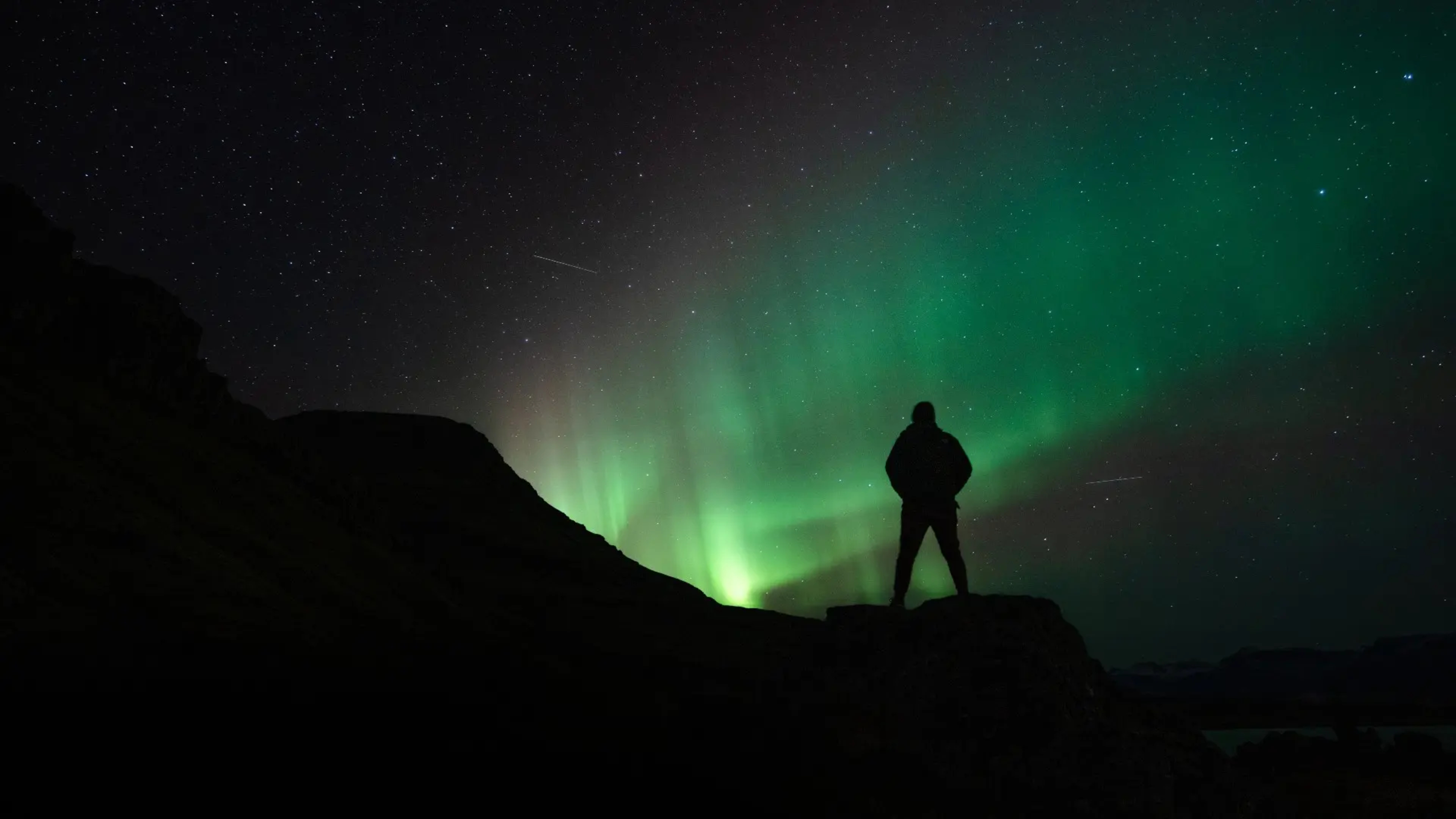 man-under-northern-lights-spenser-sembrat-unsplash.jpg.webp