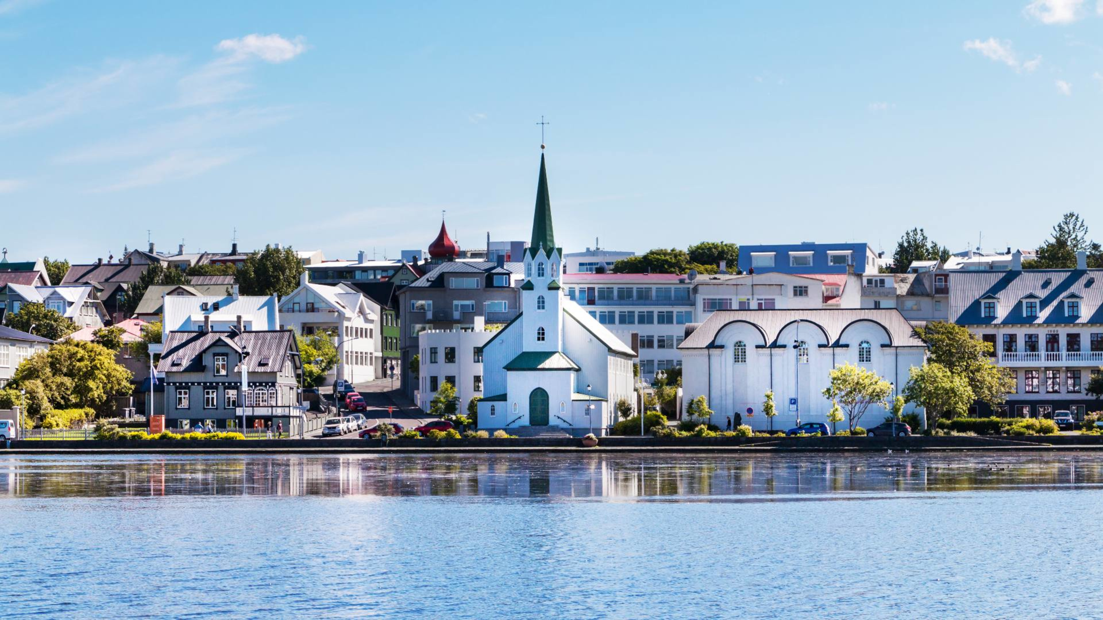The Reykjavík skyline next to the Tjörnin pond on a sunny day