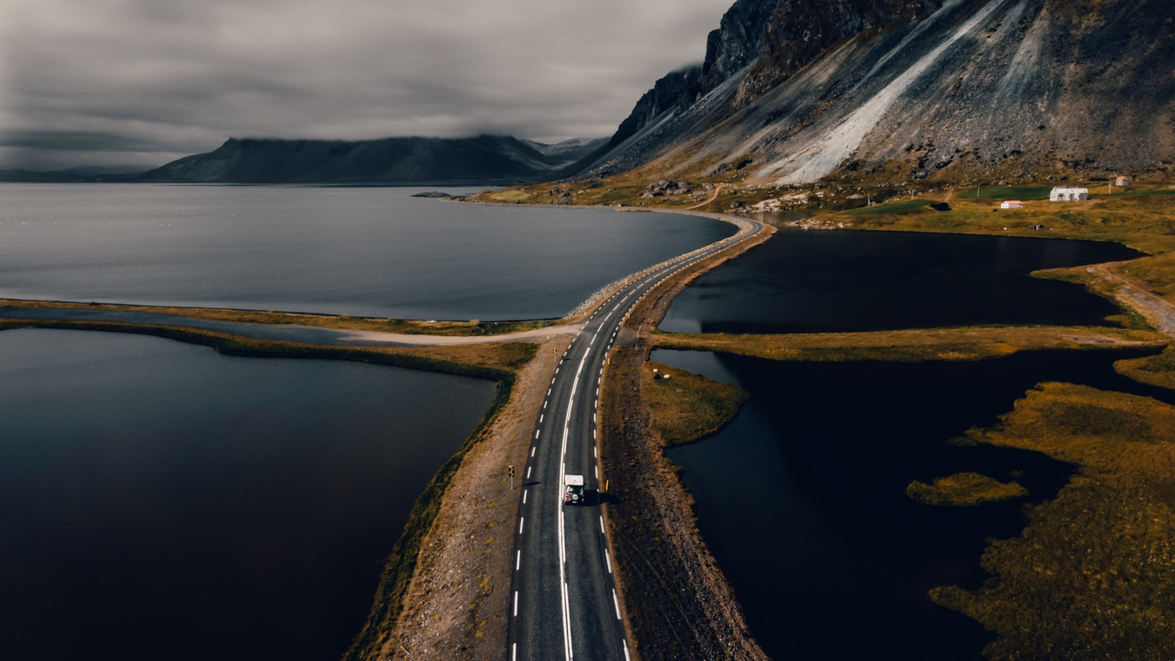An Icelandic road passing water and mountains