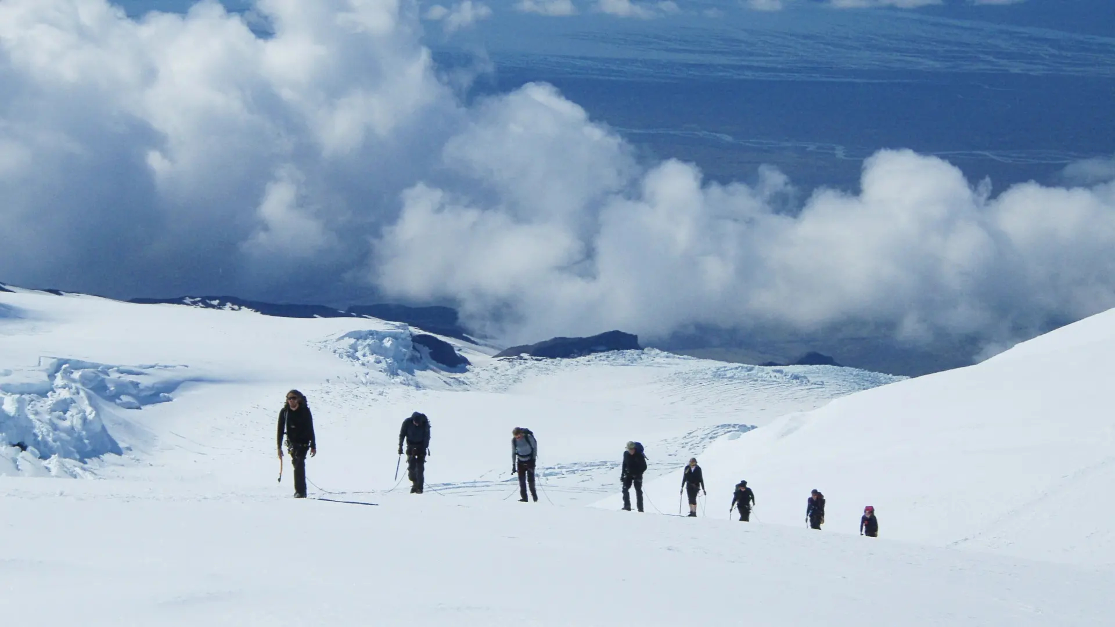 group of people walking atop a snowy glacier