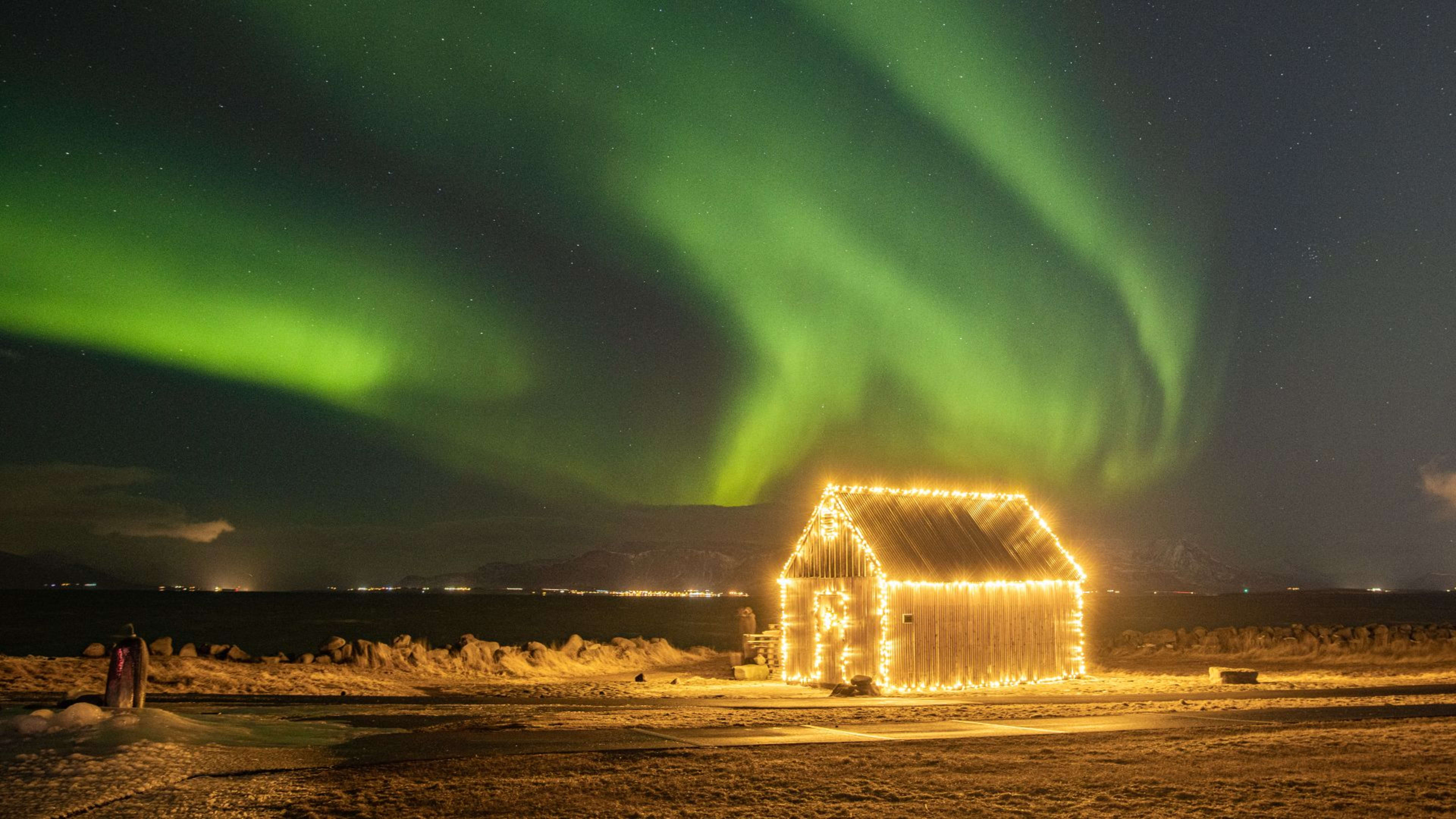 A house decorated with Christmas lights against the Northern Lights