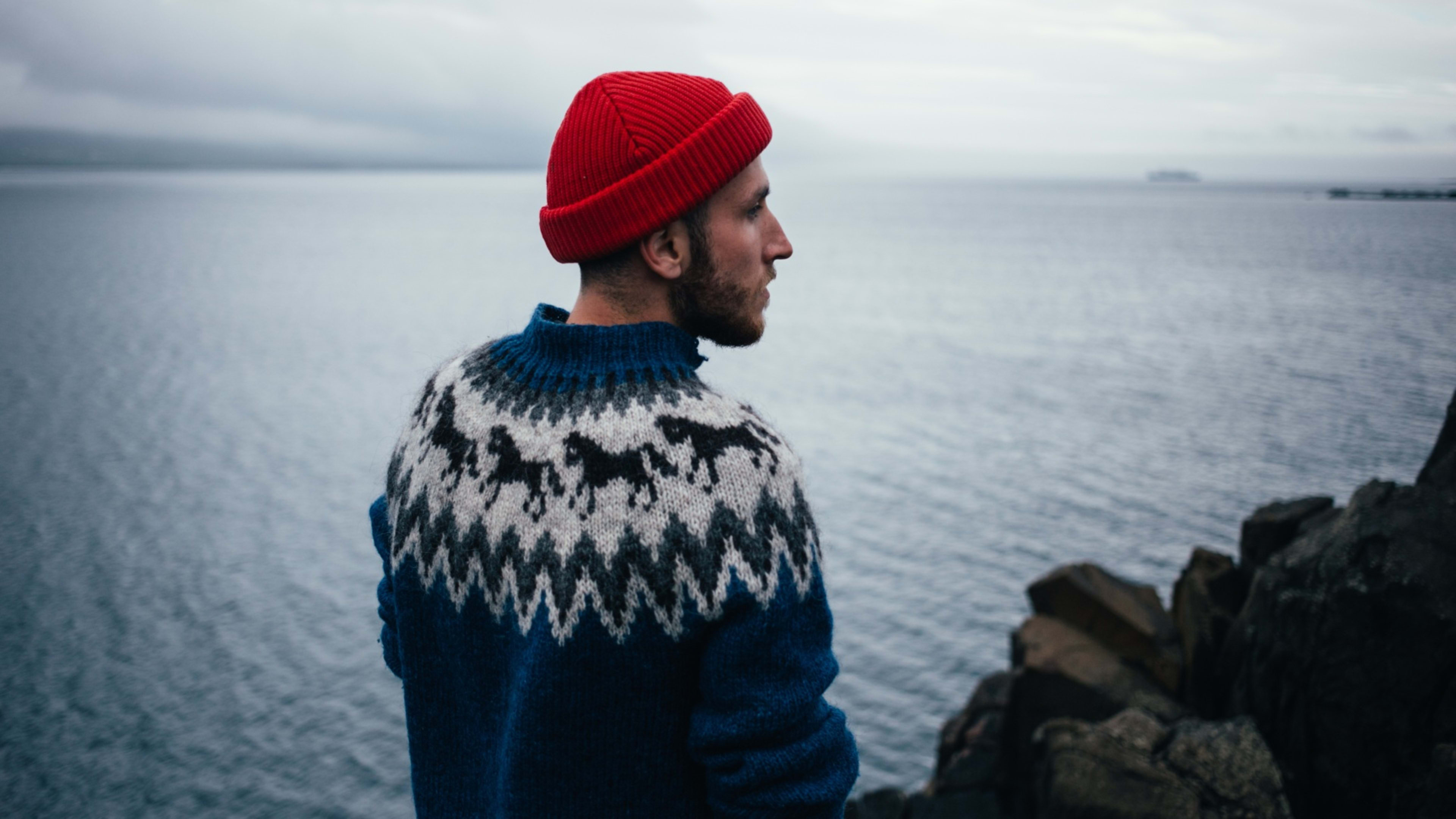 A man wearing an Icelandic sweater near the sea