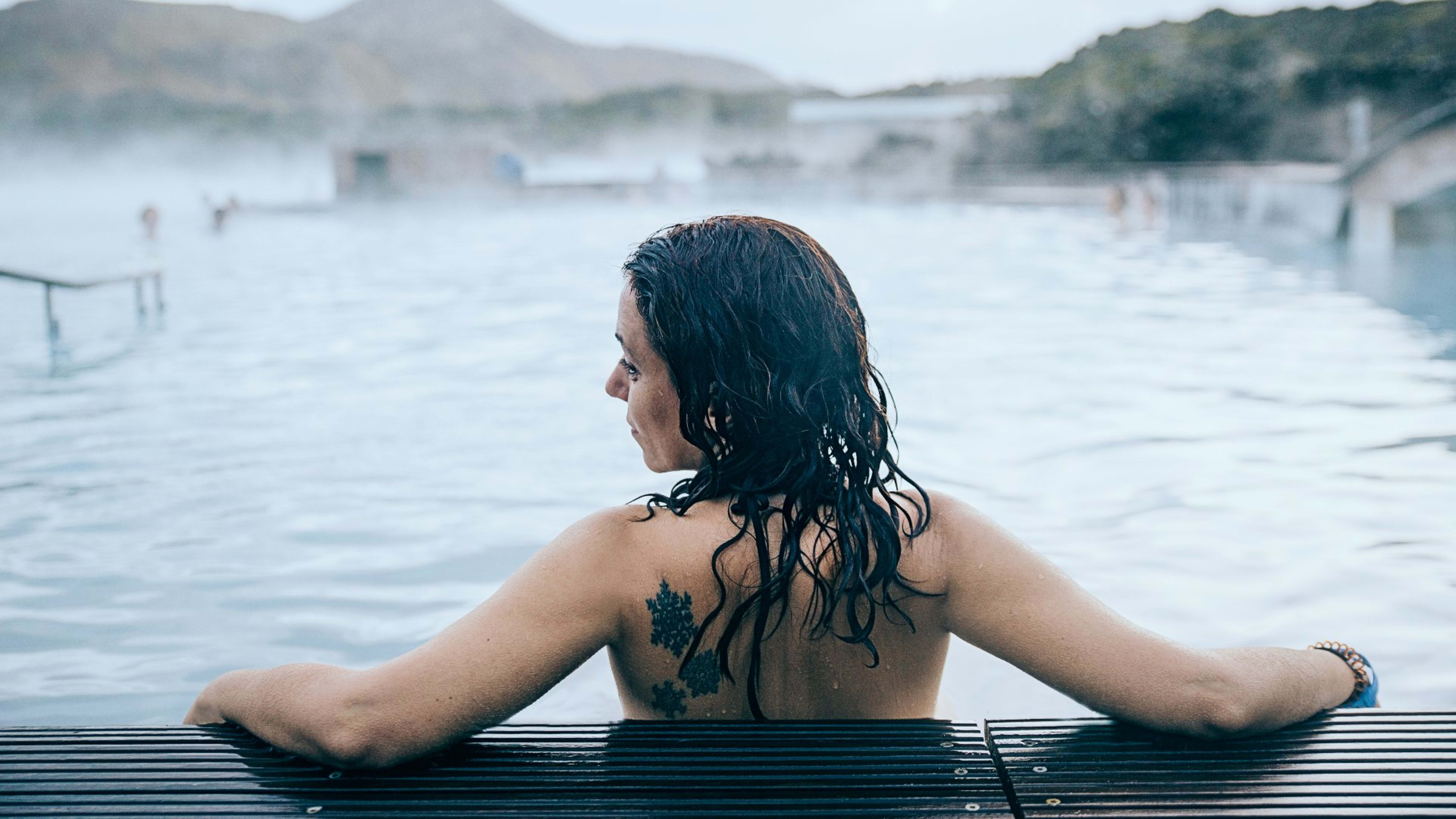 A woman with a back tattoo sitting in the Blue Lagoon