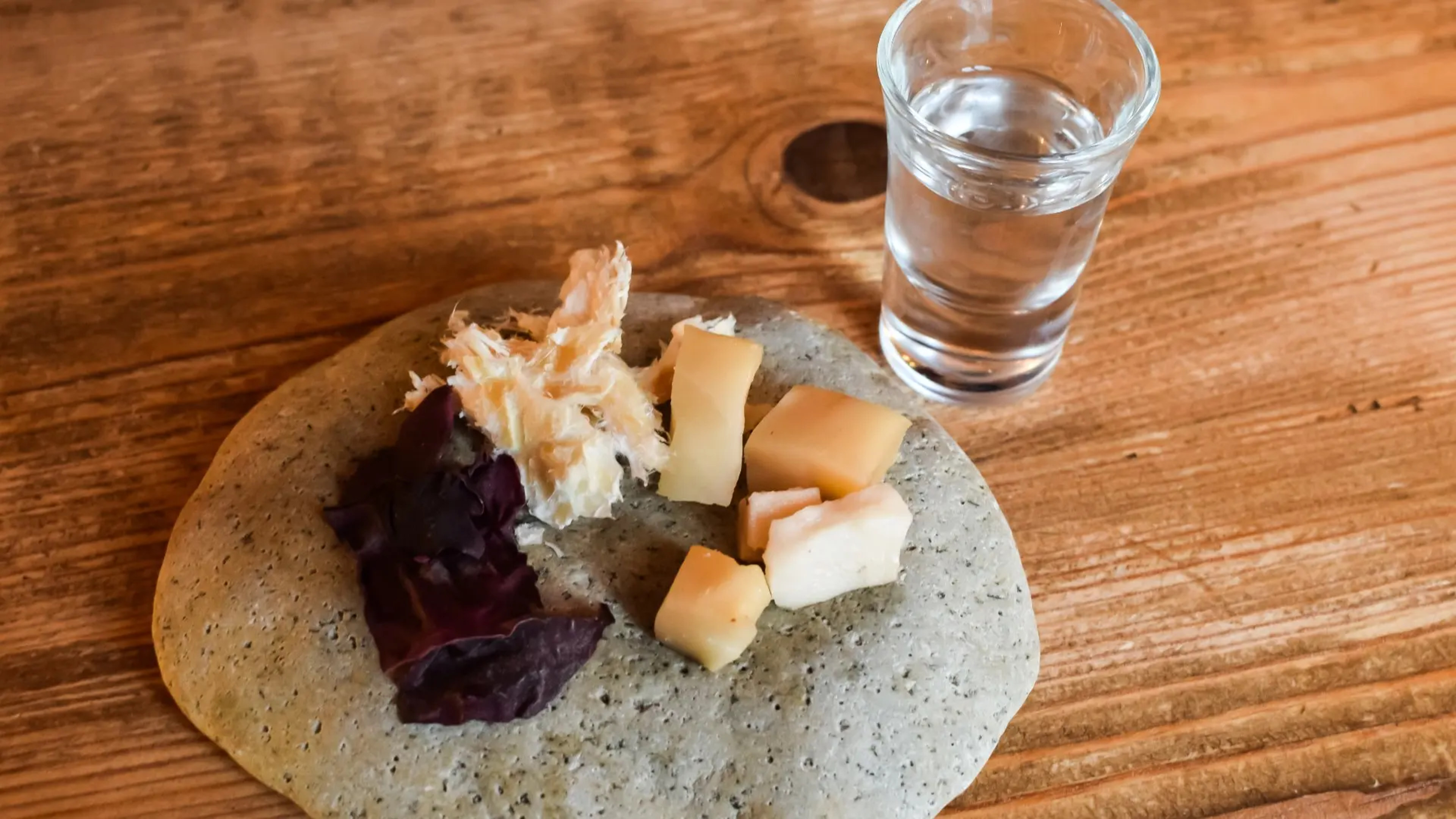 bits of traditional icelandic food on a plate with a shot of clear alcohol