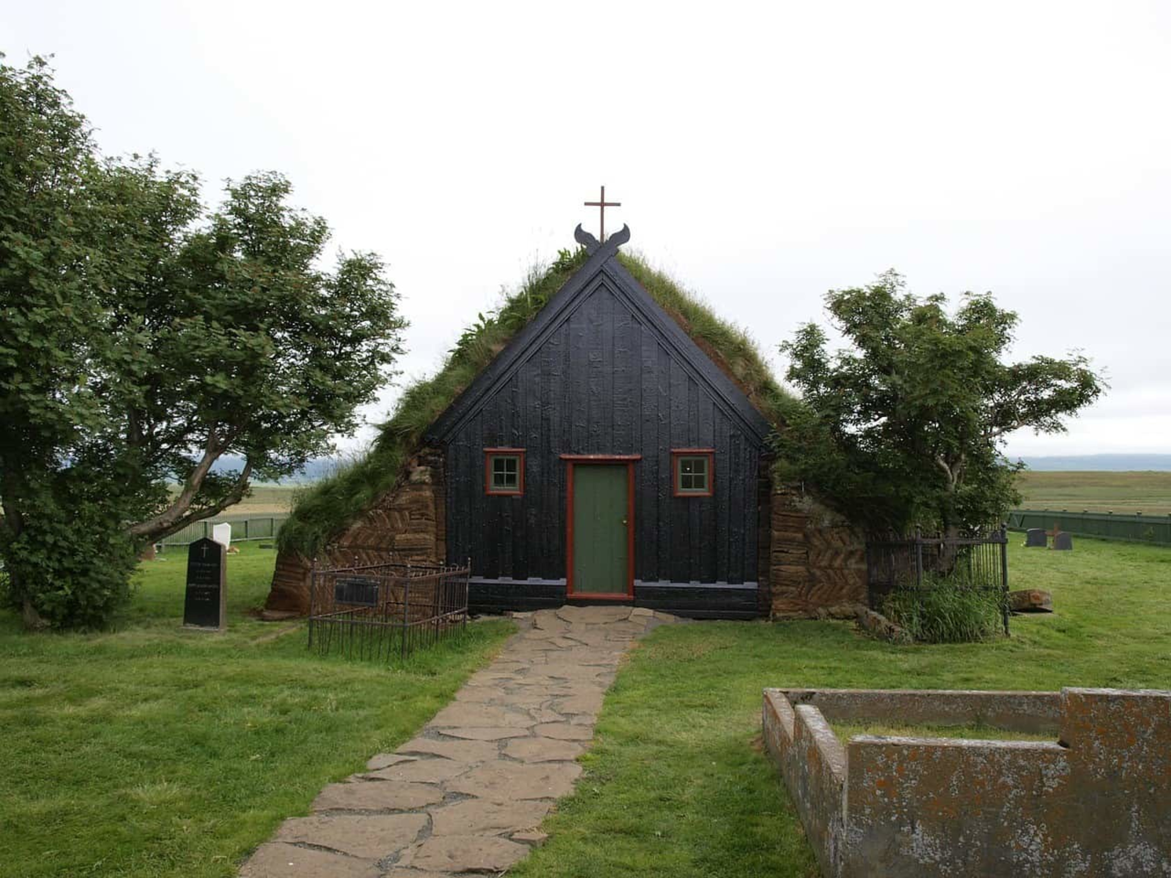 turf church with black wooden frontage and trees on either side