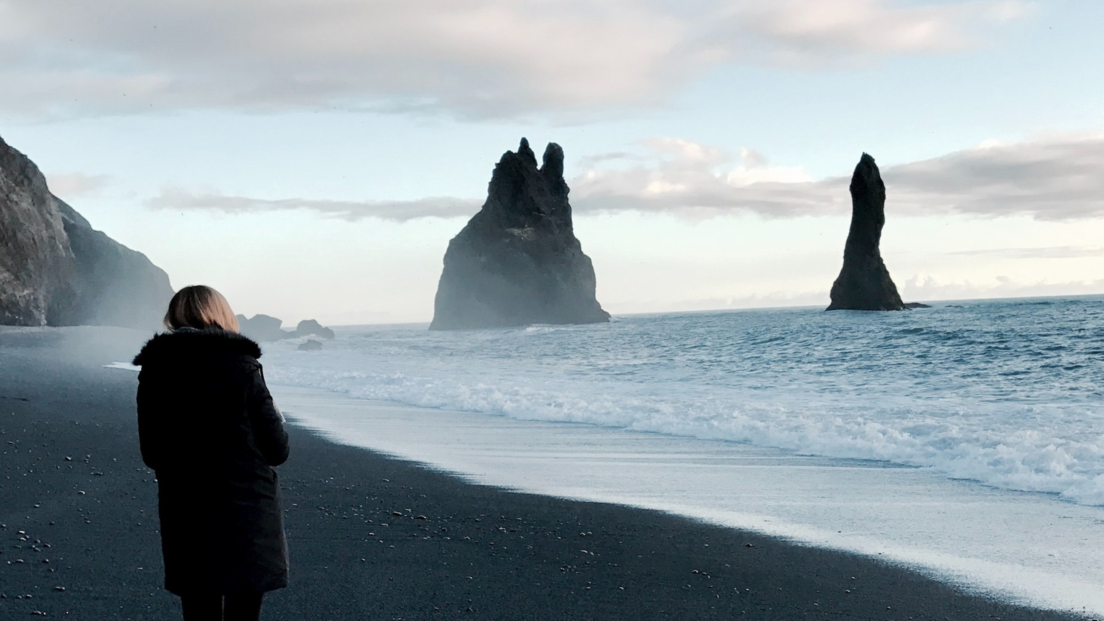 Woman walking on Reynisfjara black sand beach in Iceland