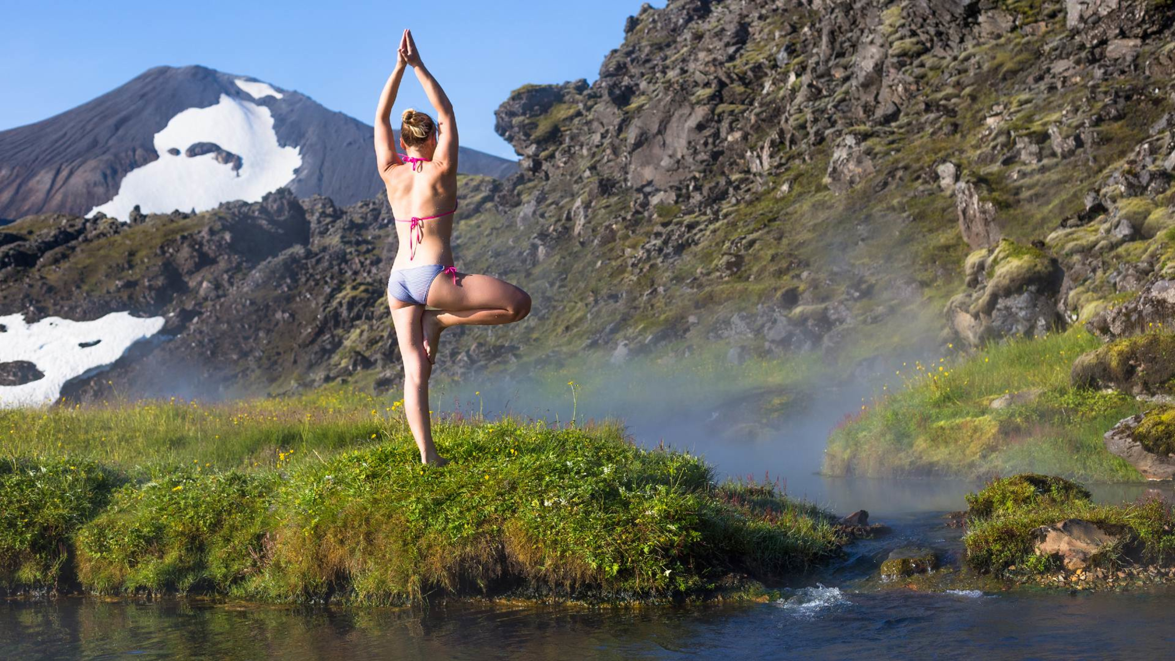 A woman doing yoga at the hot springs of Landmannalaugar