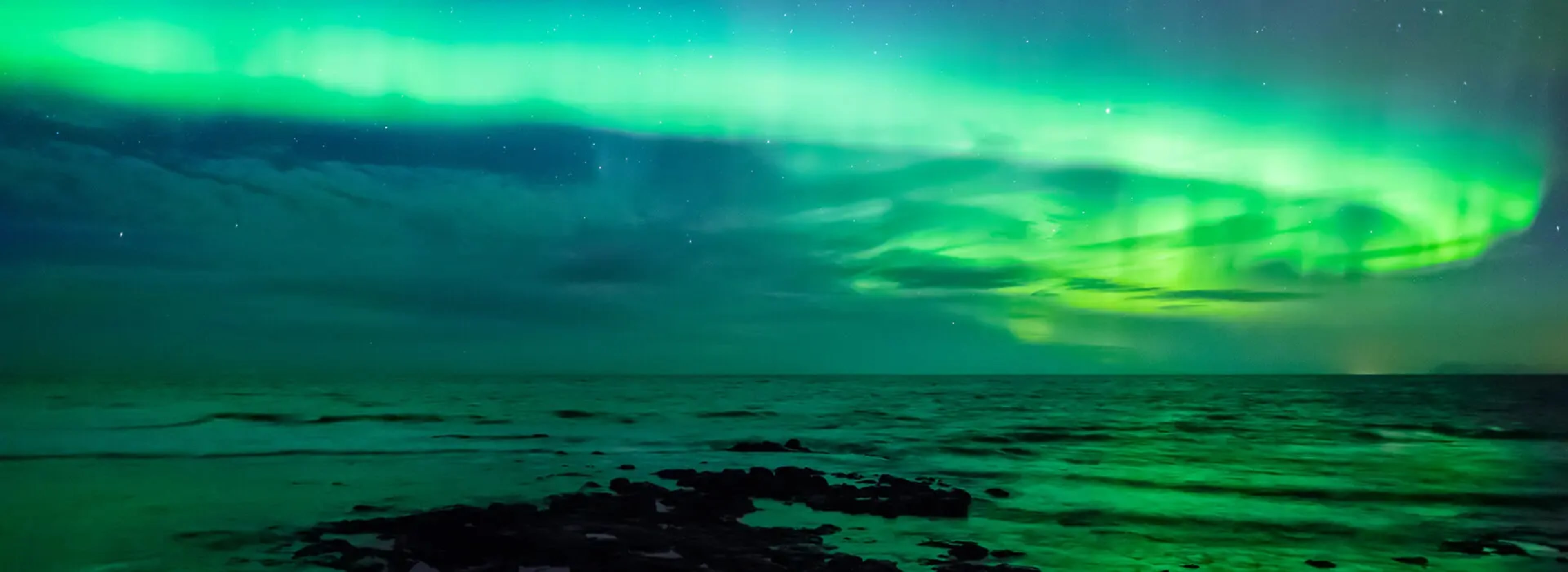 Northern Lights illuminates the sky above the sea in Iceland