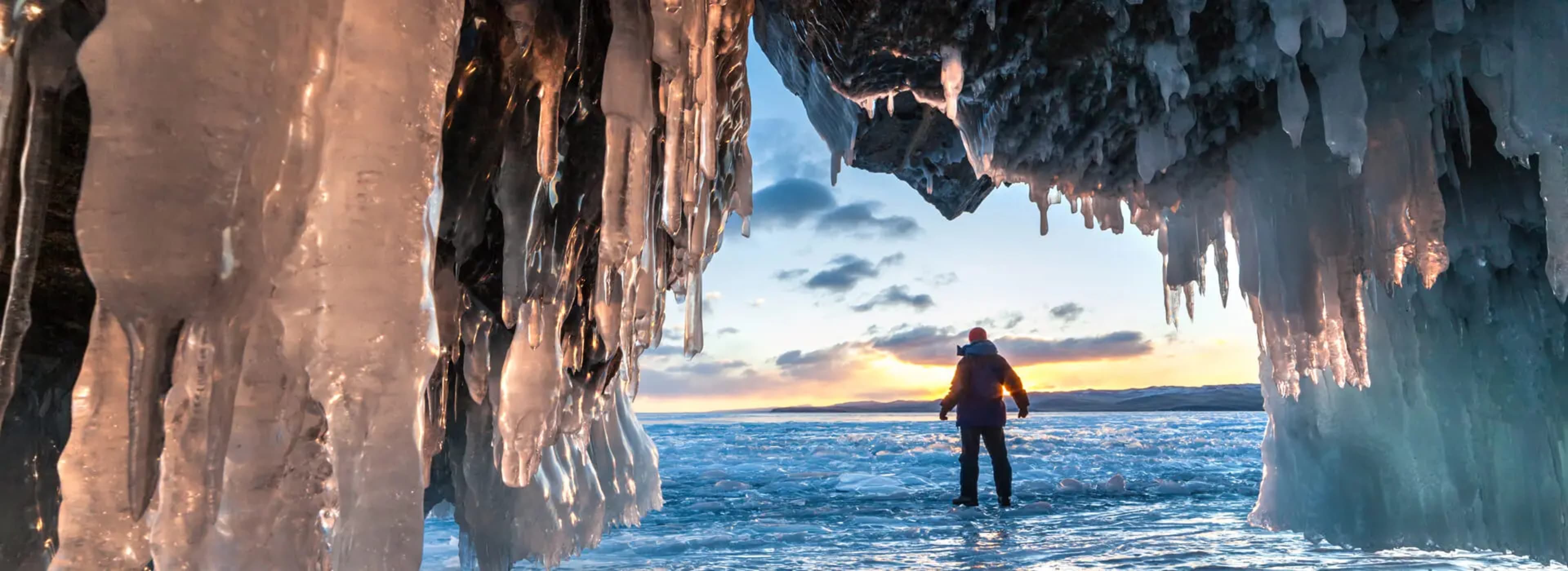 Person admiring the sunrise from an ice cave