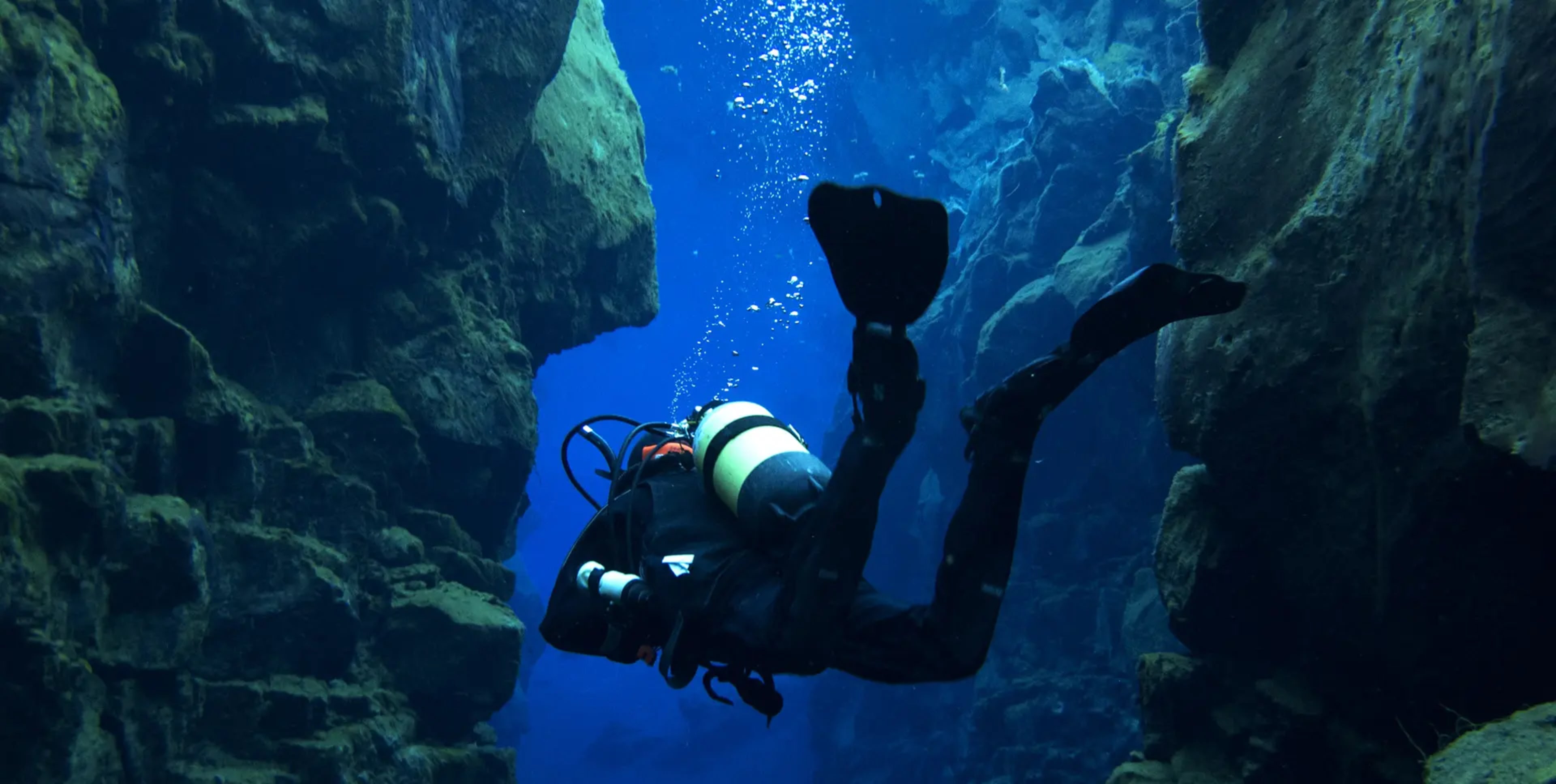 person scuba diving in underwater fissure