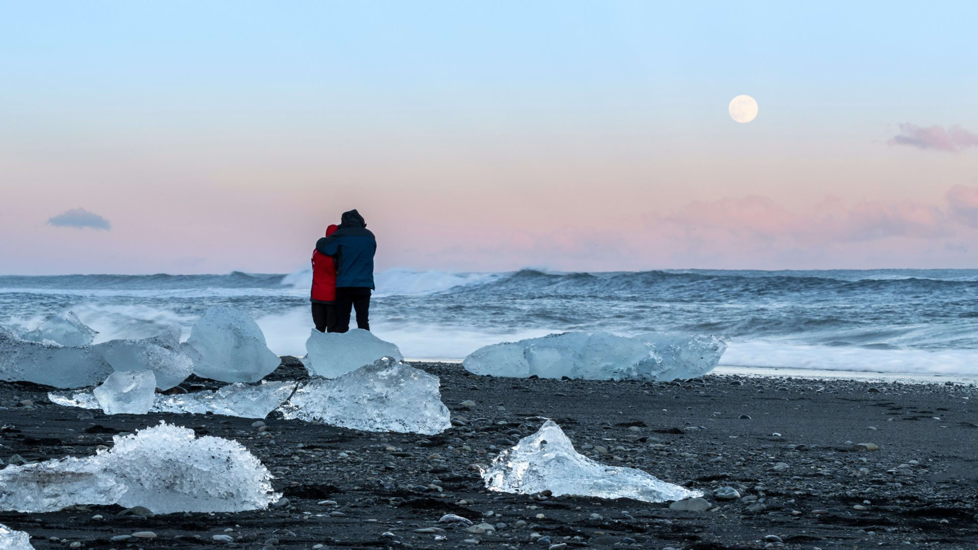 A couple standing on Fellsfjara, Diamond Beach, at sunset